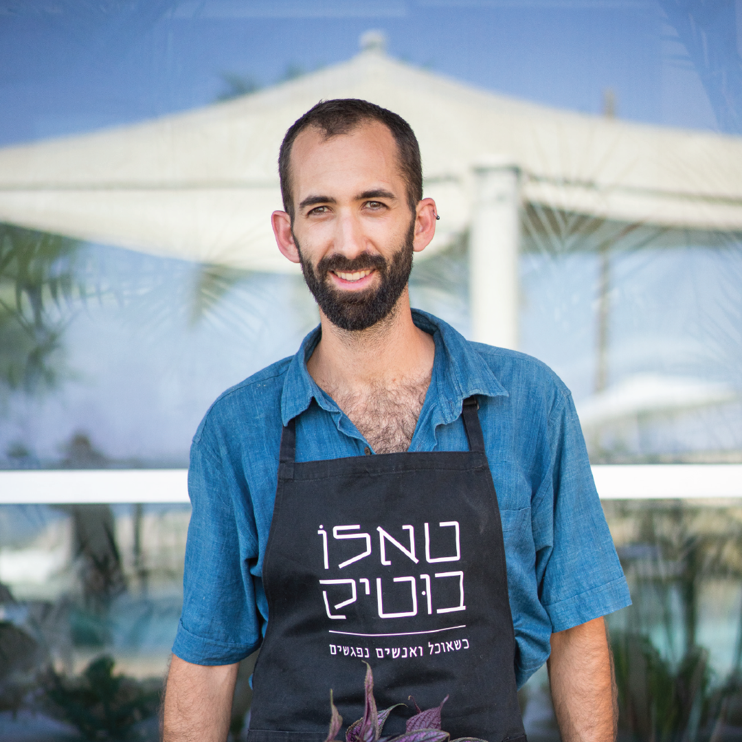 אמיר מהצוות עומד מול המצלמה בחולצה כחולה וסינר טאלו בוטיק